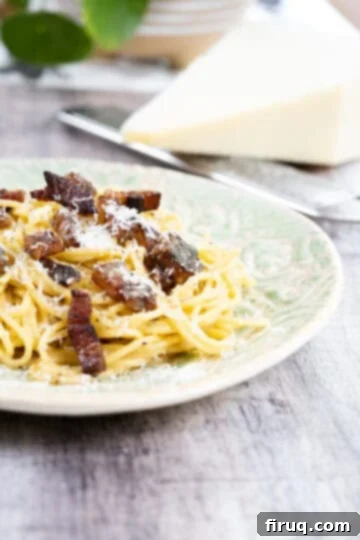 The Ultimate Carbonara Do's and Don'ts 13 Finished spaghetti carbonara on a plate topped with extra pecorino, highlighting the use of guanciale.