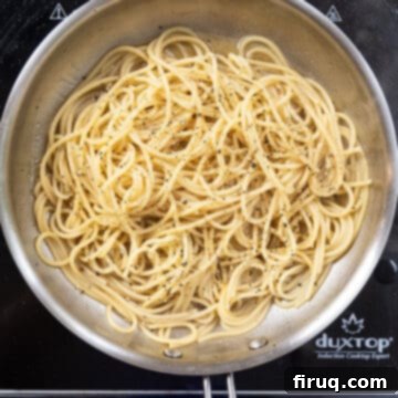The Ultimate Carbonara Do's and Don'ts 8 Hot, cooked spaghetti being added to the saucepan with rendered fat and black pepper, ready to be combined.