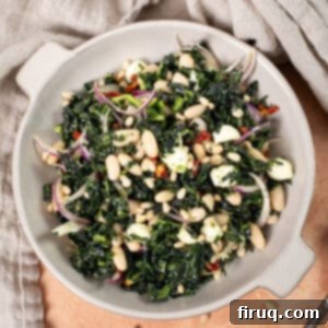 Hearty Kale and White Bean Salad 9 A beautifully presented Kale and Cannellini Bean salad in a large bowl, garnished with toasted pine nuts. The vibrant green of the kale contrasts with the white beans and red sundried tomatoes.