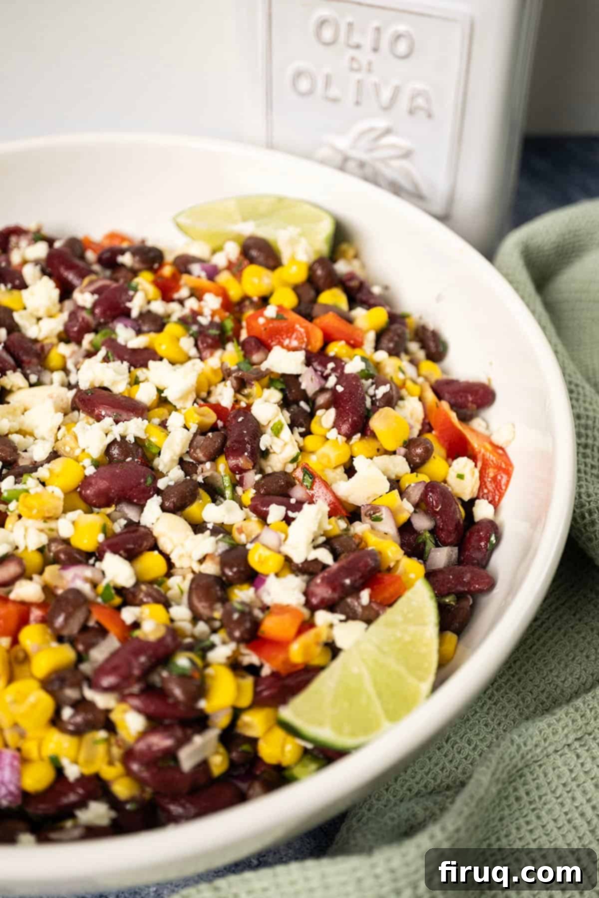Tex-Mex Treasure Salad 7 A beautifully presented serving bowl of chilled Cowboy Caviar Salad, artfully garnished with fresh lime wedges and a delicate sprinkle of fresh cilantro, ready to be enjoyed as a refreshing side or dip.