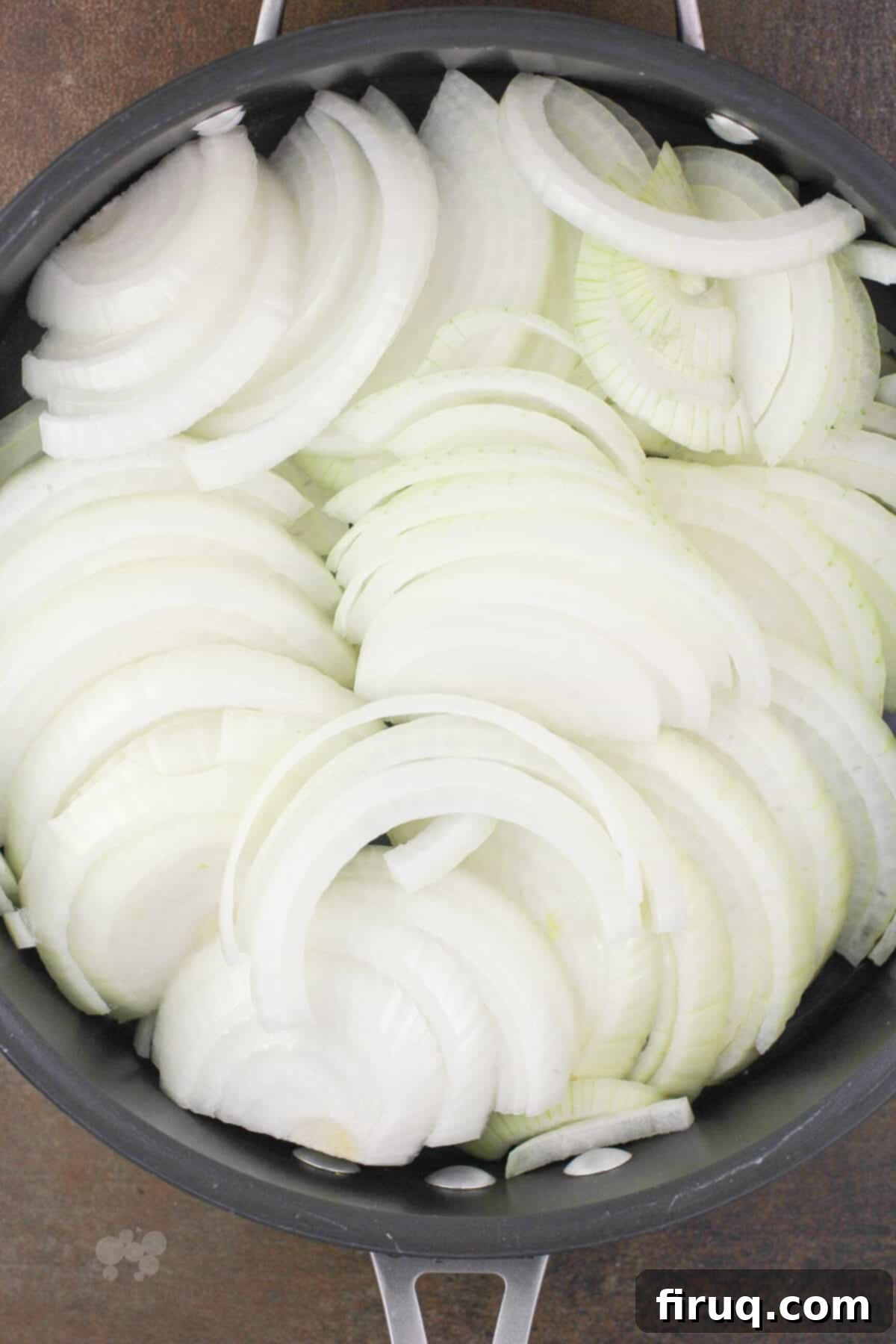 Sticky Honey Bourbon Onions 4 Thinly sliced white onions in a skillet, ready for the caramelization process.