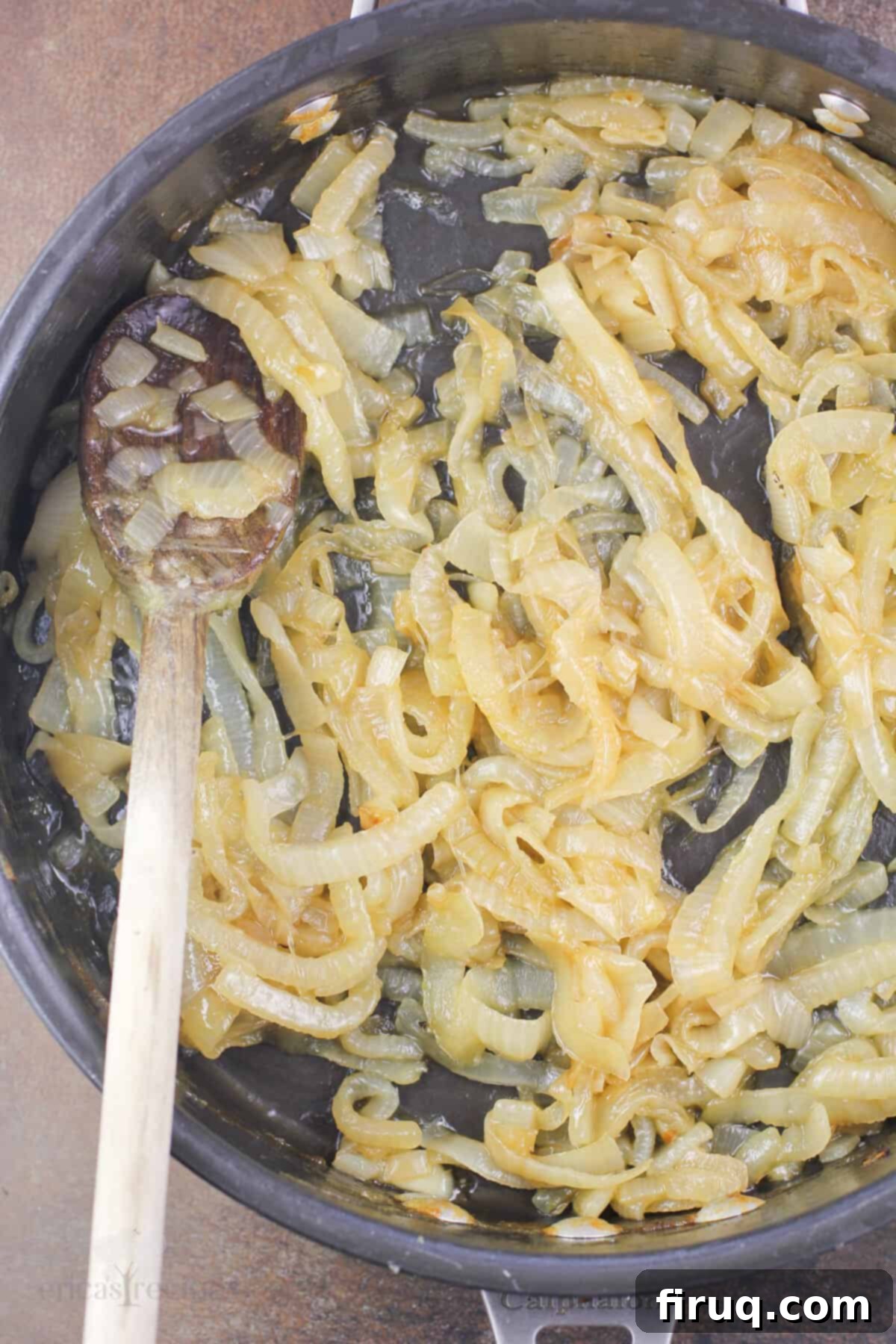 Sticky Honey Bourbon Onions 7 Prepared bourbon caramelized onions in a skillet with a wooden spoon, glistening with honey and bourbon.