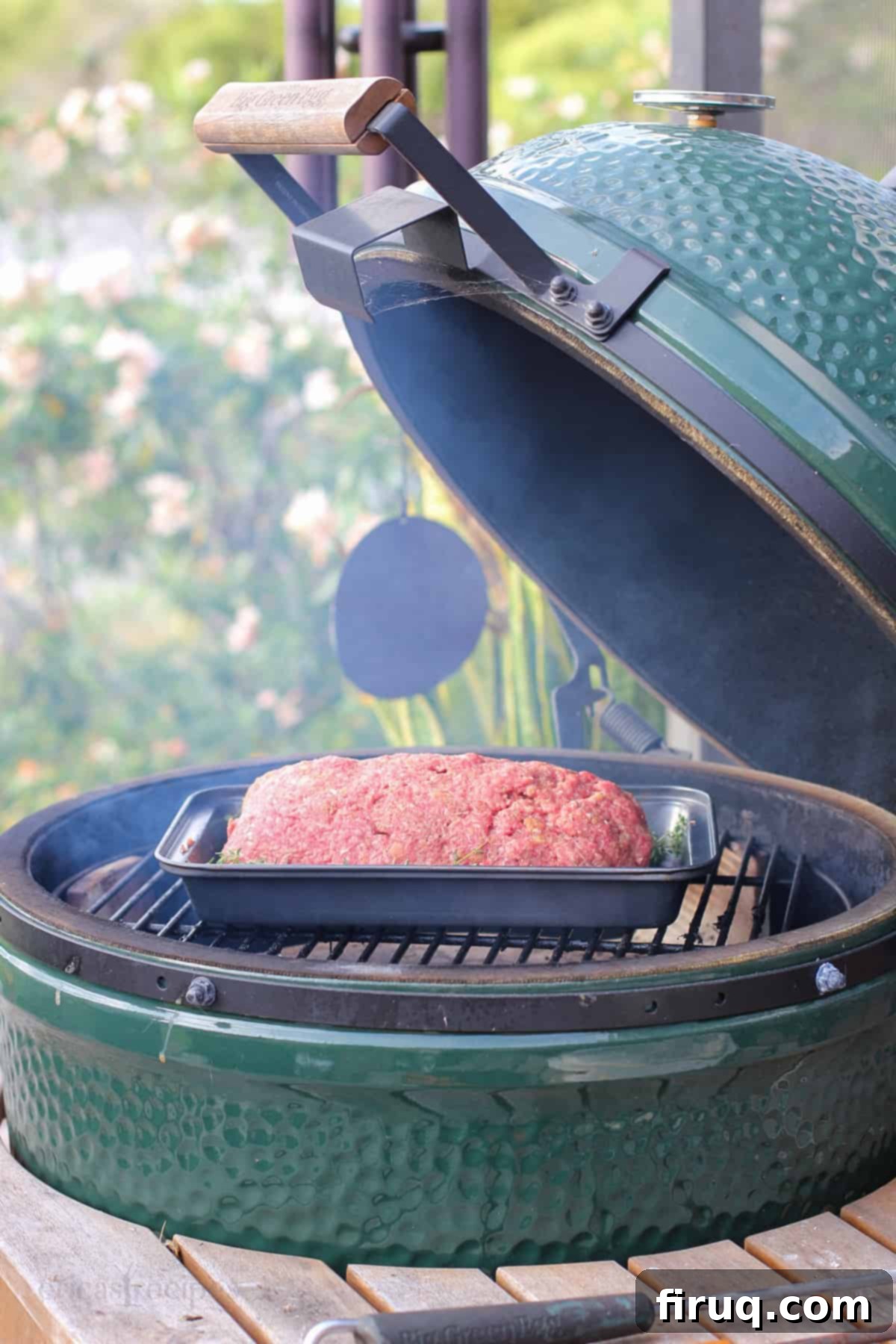 Signature Smoked Meatloaf 5 Smoked meatloaf cooking on the grate inside an open Big Green Egg smoker, with visible smoke, ensuring an even cook.
