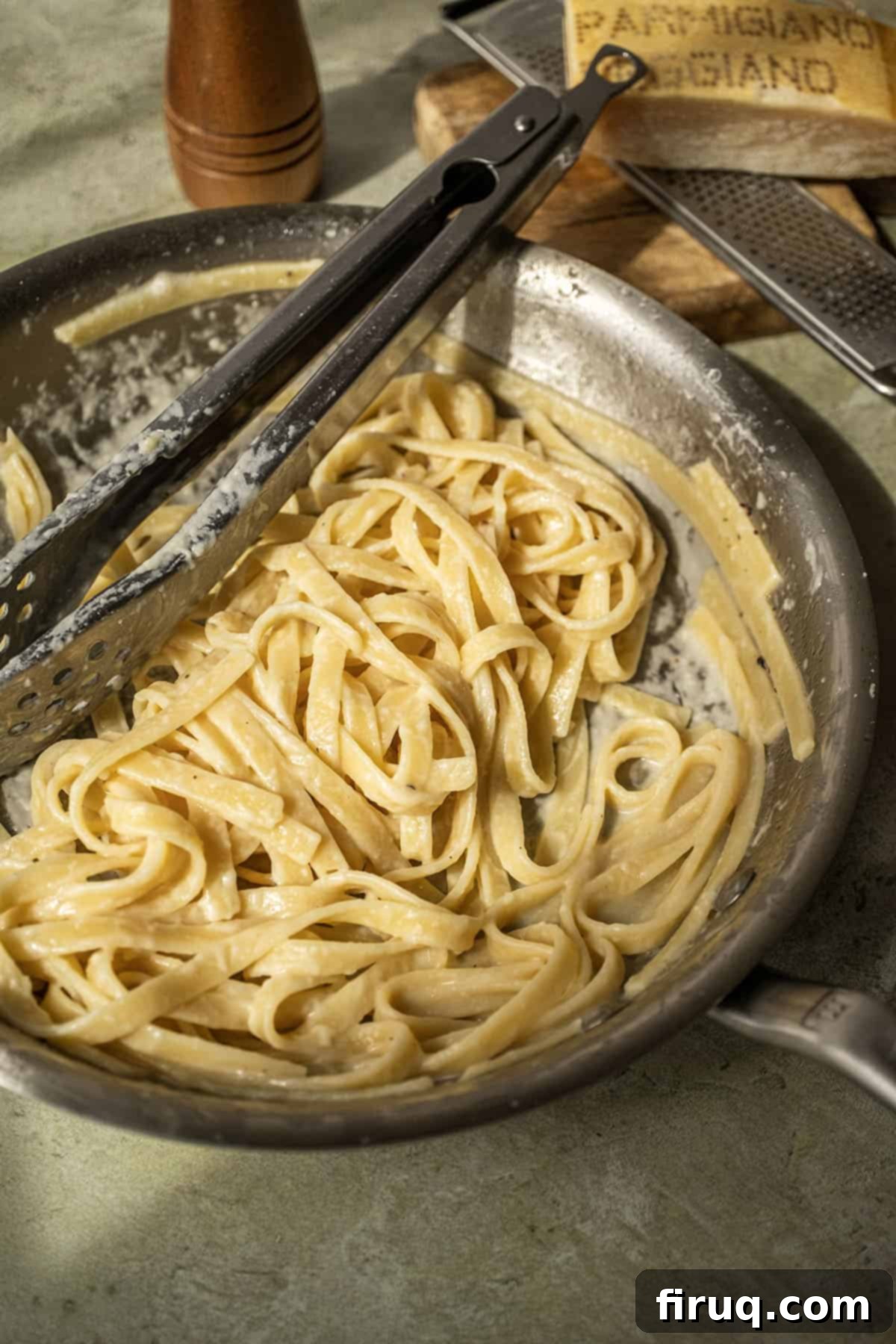 Classic Fettuccine Alfredo 2 Fettuccine in alfredo sauce in a pan with tongs, ready to serve.