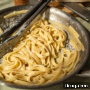 Classic Fettuccine Alfredo 11 Fettuccine in alfredo sauce in a pan with tongs, perfectly creamy.