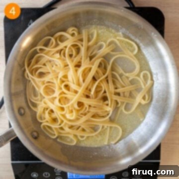 Classic Fettuccine Alfredo 7 Adding al dente fettuccine pasta to the pan with butter and pasta water, then tossing.