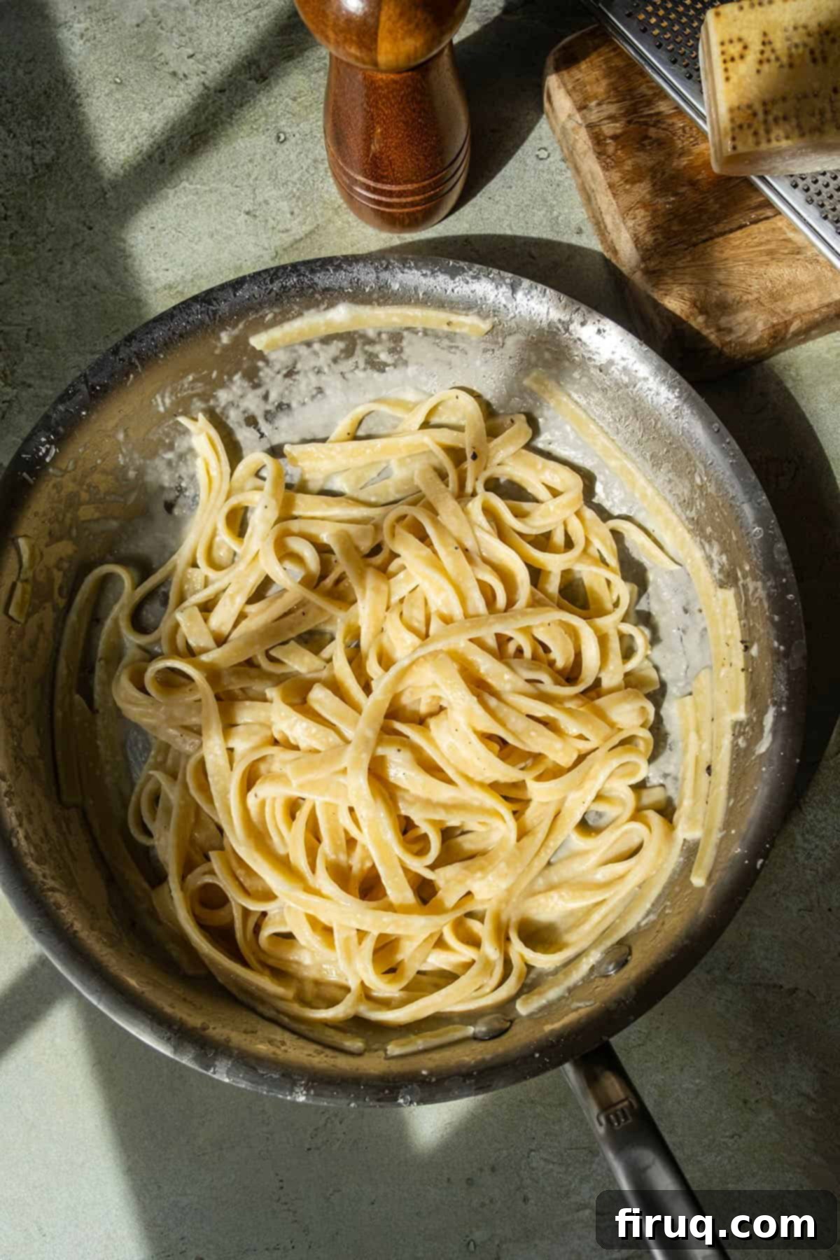 Classic Fettuccine Alfredo 10 Fettuccine alfredo in a pan, garnished with fresh Parmigiano-Reggiano and cracked black pepper on the side.