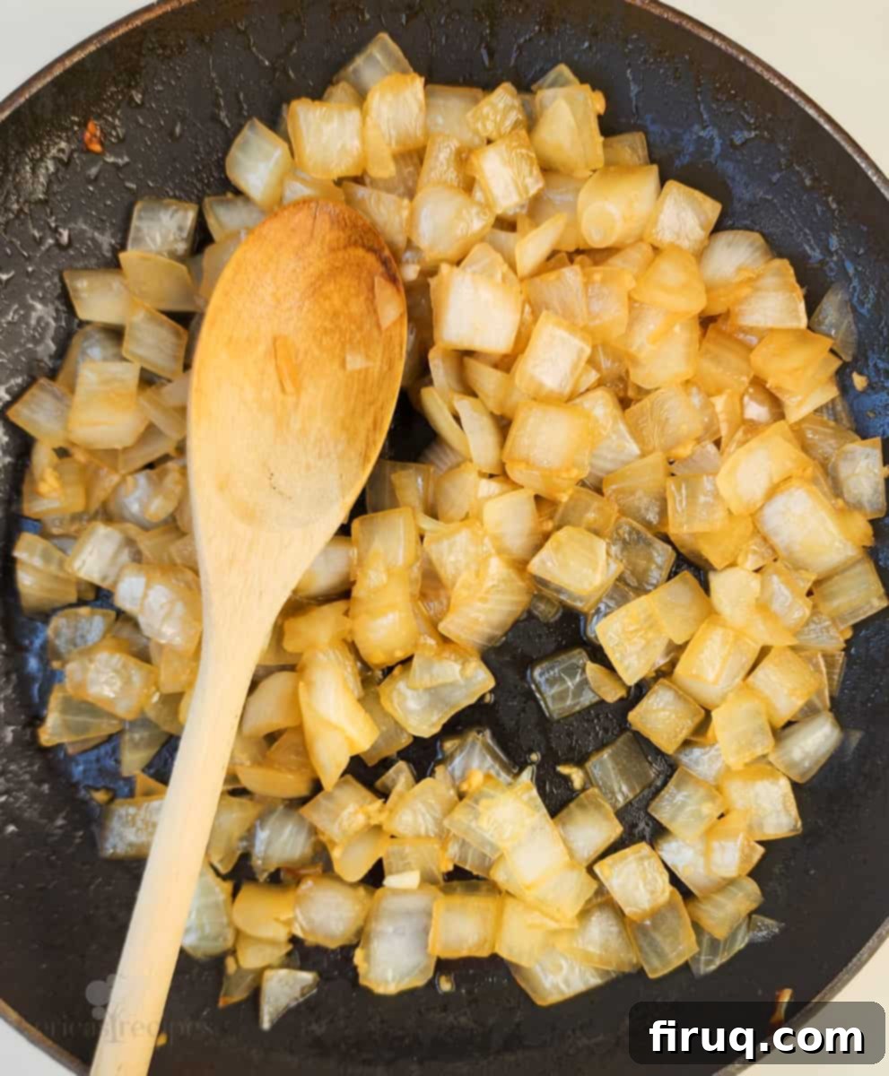 Velvety Poblano Mac and Cheese 5 Cooked onions and garlic in a skillet with a wooden spoon