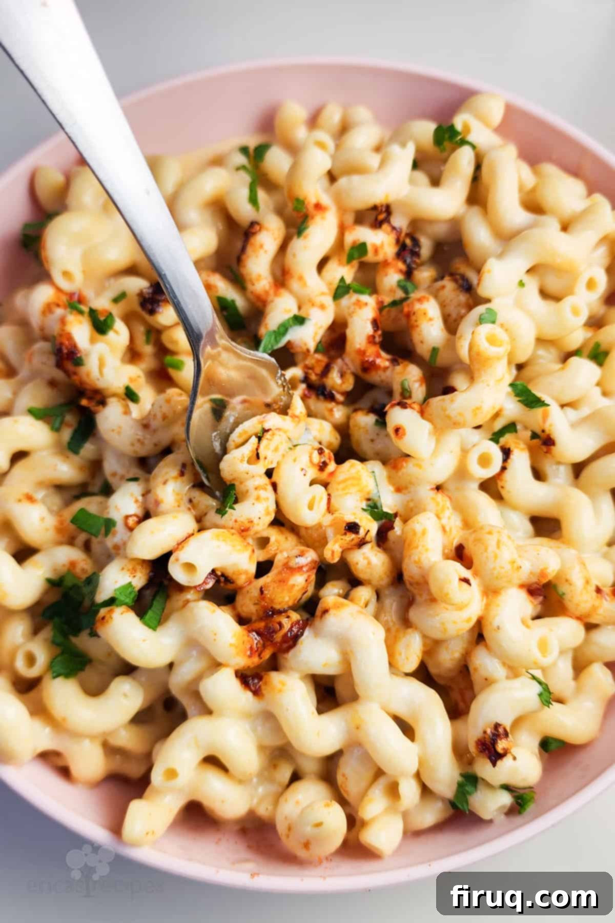 Cottage Comfort Mac 2 A vibrant pink bowl filled with creamy cottage cheese mac and cheese, with a fork resting inside, ready to be enjoyed.