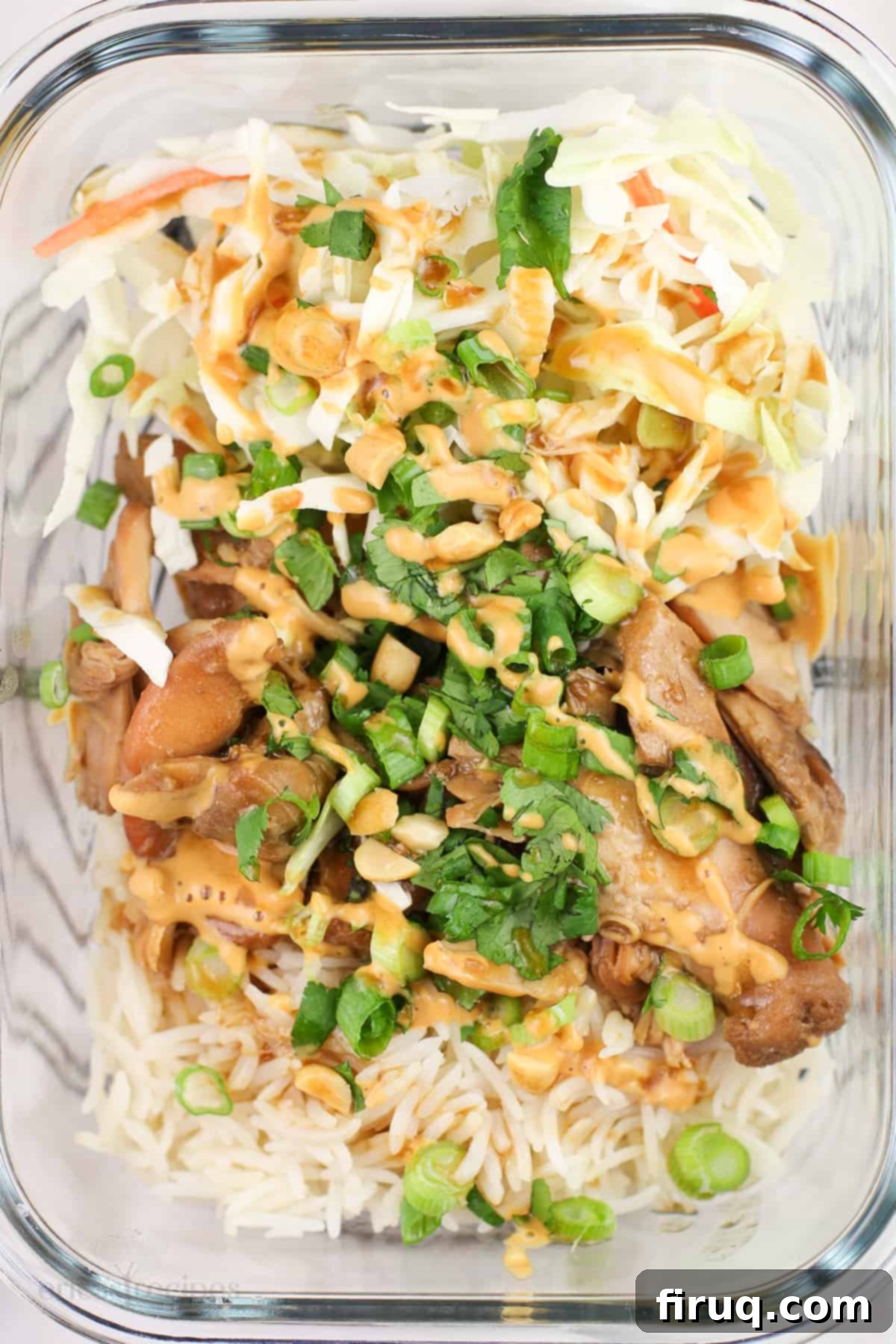 Sweet and Sticky Honey Teriyaki Chicken Meal Prep 3 A close-up of a glass meal prep container filled with slow cooker honey teriyaki chicken, white rice, and fresh shredded cabbage.