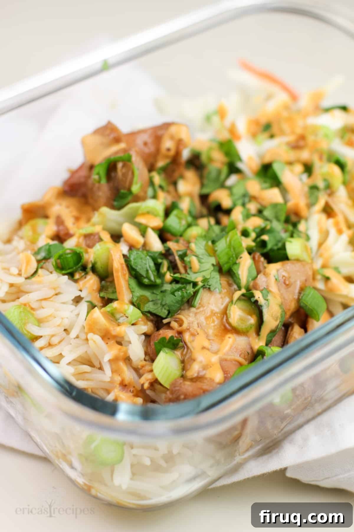 Sweet and Sticky Honey Teriyaki Chicken Meal Prep 4 A top-down view of a glass meal prep container with slow cooker honey teriyaki chicken, rice, and fresh garnishes.