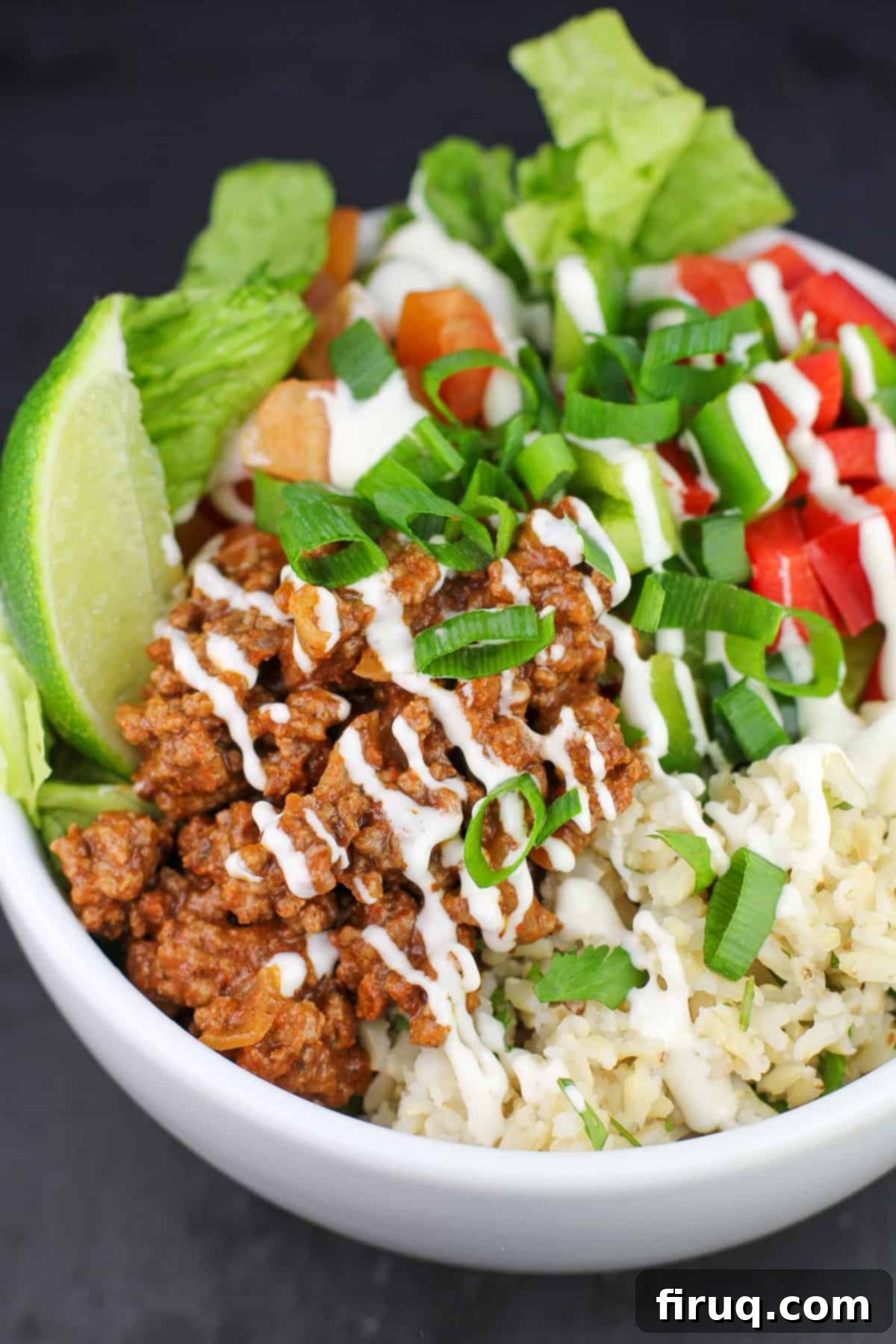 Game-Changing Ground Beef Tacos 3 white bowl with taco meat, veggies, lettuce, brown rice, and a lime wedge