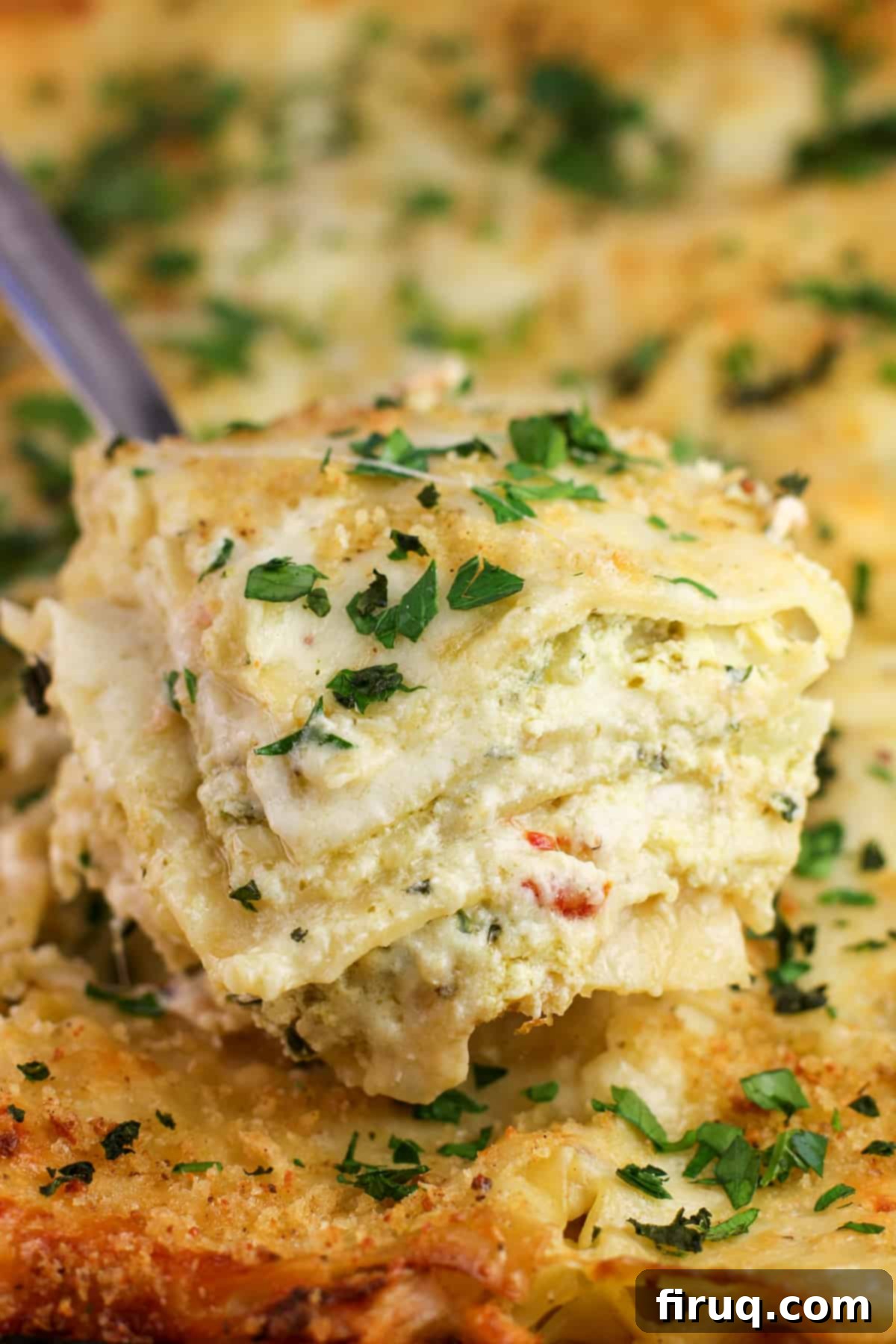 Rich Pesto Salmon Lasagna 2 close view of a spatula holding a large square of pesto salmon lasagna to show the layers