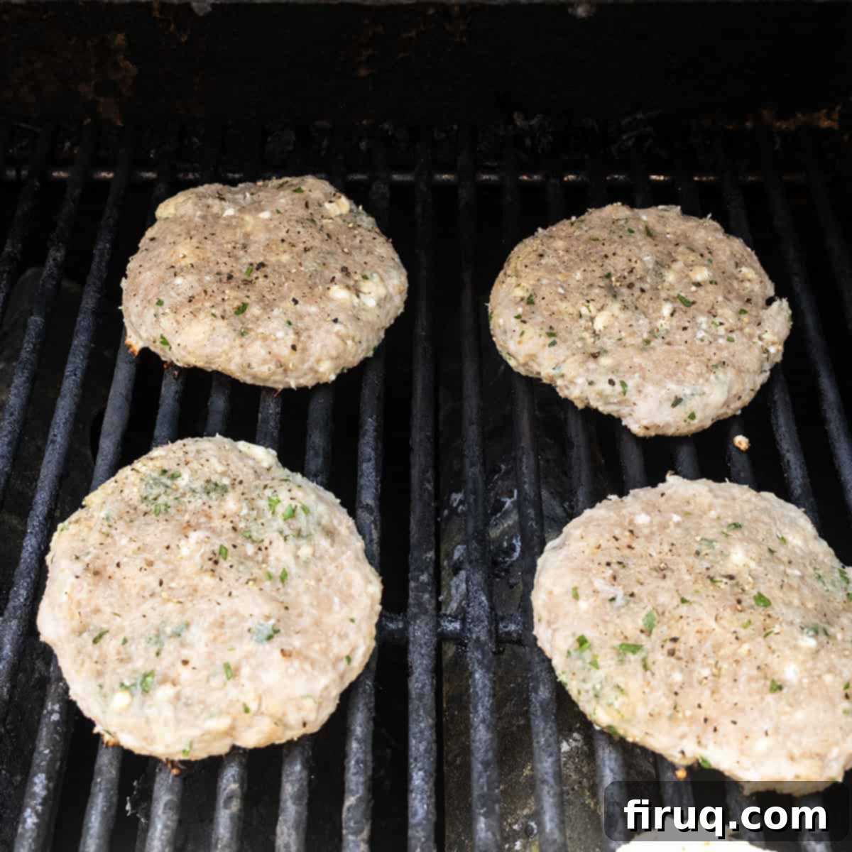 Gourmet Gorgonzola Grilled Chicken Burger 6 Close-up shot of several chicken burgers grilling over open flames on a barbecue, showing a golden-brown crust.
