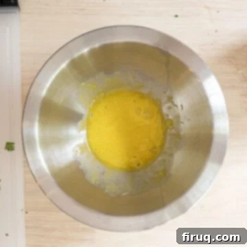 Gourmet Gorgonzola Grilled Chicken Burger 7 A hand slowly whisking together olive oil, egg yolk, and grated garlic in a small bowl, beginning the emulsification process for aioli.