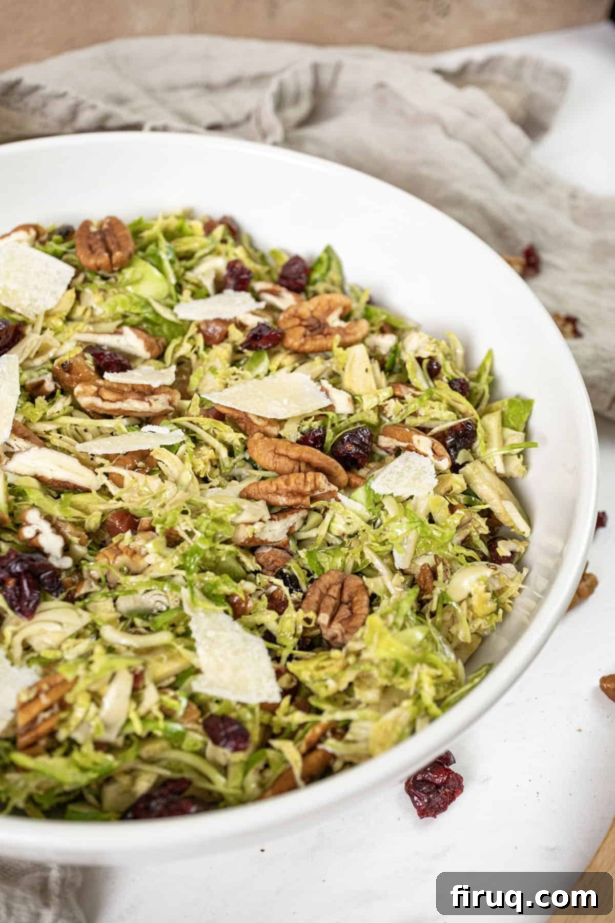 Brussels Sprout Salad with Crispy Pancetta 2 Brussels sprouts salad in a bowl topped with dried cranberries and pecans.
