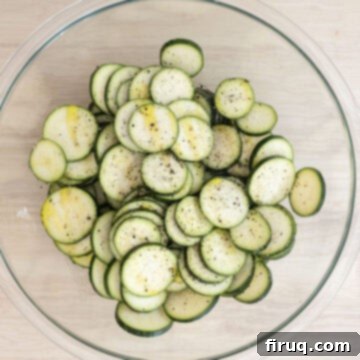 Zesty Marinated Zucchini 6 Zucchini slices in a bowl, drizzled generously with olive oil and seasoned with salt and pepper.