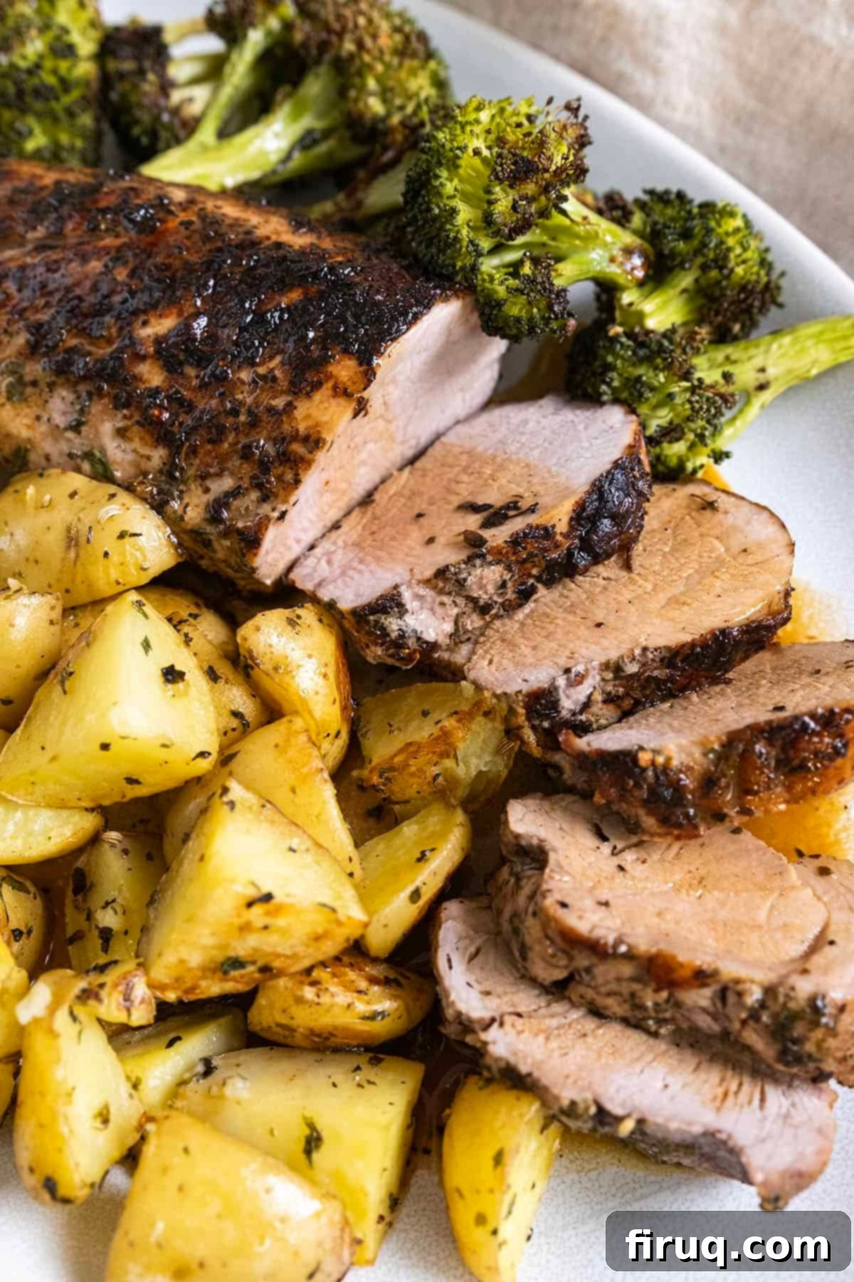 Rustic Italian Cast Iron Pork Tenderloin 2 Sliced pork tenderloin served on a plate with roasted potatoes and broccoli, drizzled with garlic butter wine sauce.
