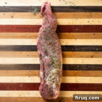 Rustic Italian Cast Iron Pork Tenderloin 4 Seasoned pork tenderloin on a cutting board, ready for searing.