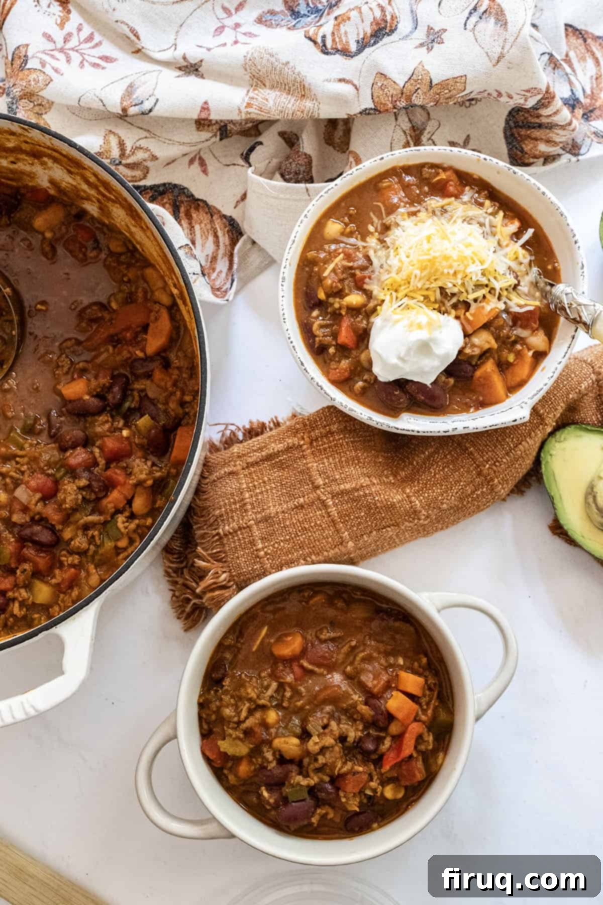Golden Harvest Chili 13 Two bowls of white bean pumpkin chili, one topped with sour cream and cheese, and a Dutch oven full of chili.