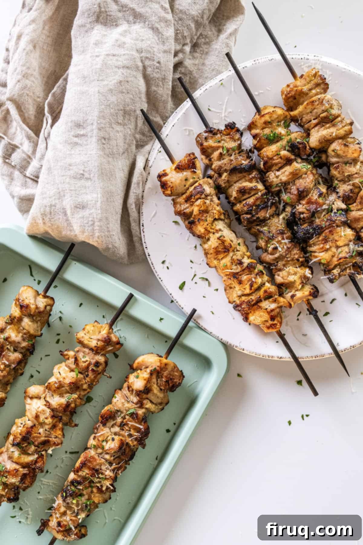 Irresistible Garlic Parmesan Chicken Skewers 11 Garlic parm chicken skewers on a plate basted with parm sauce.