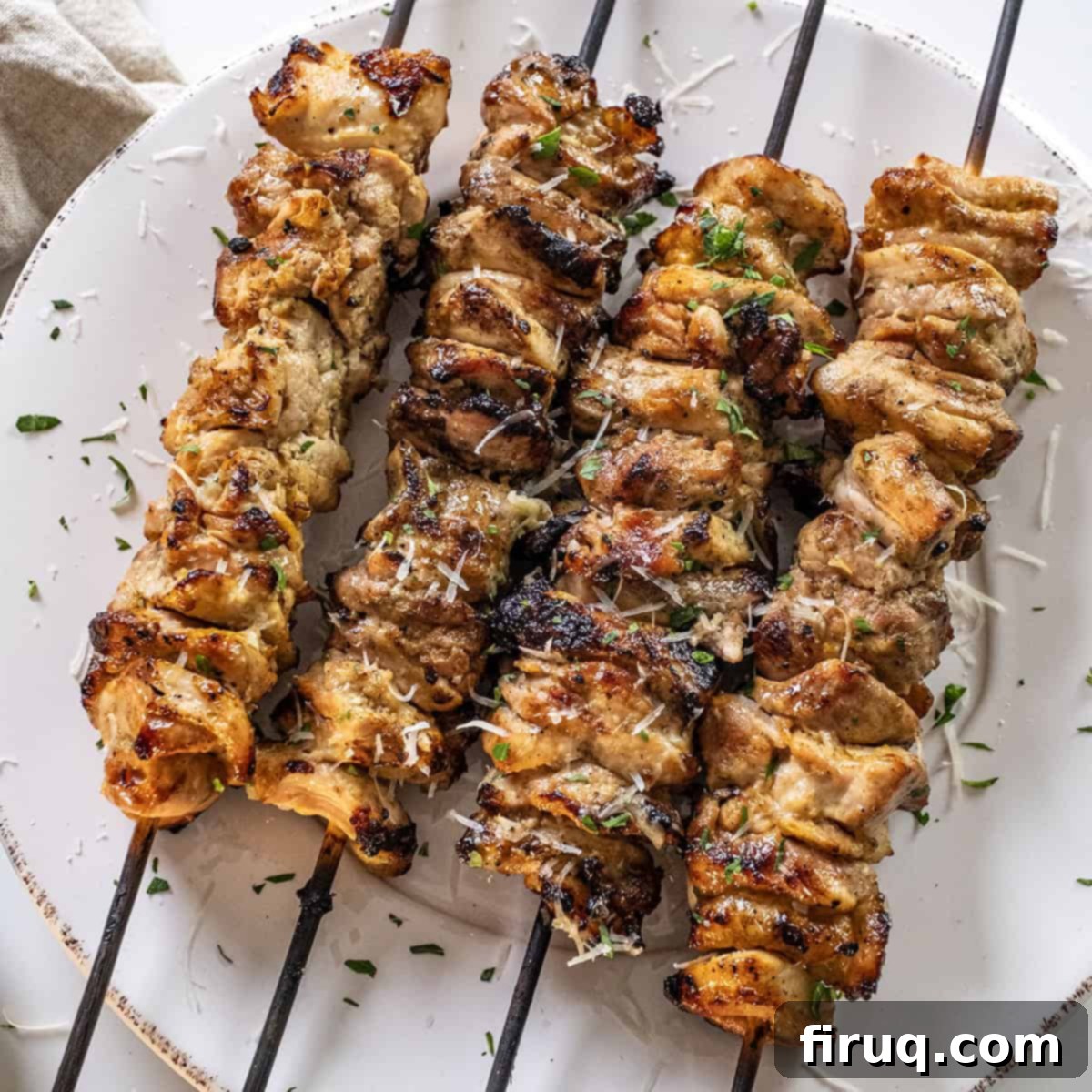 Irresistible Garlic Parmesan Chicken Skewers 10 Garlic parm chicken skewers on a plate basted with parm sauce.