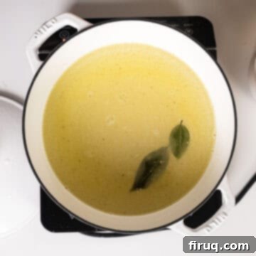 Velvety Smooth Polenta 4 Whisking together cold water, olive oil, salt, bay leaves, and polenta in a large pot, showing the initial cloudy mixture.