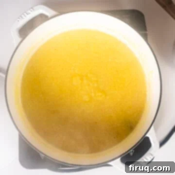 Velvety Smooth Polenta 5 Polenta simmering gently in a Dutch oven, being stirred with a whisk to prevent sticking.