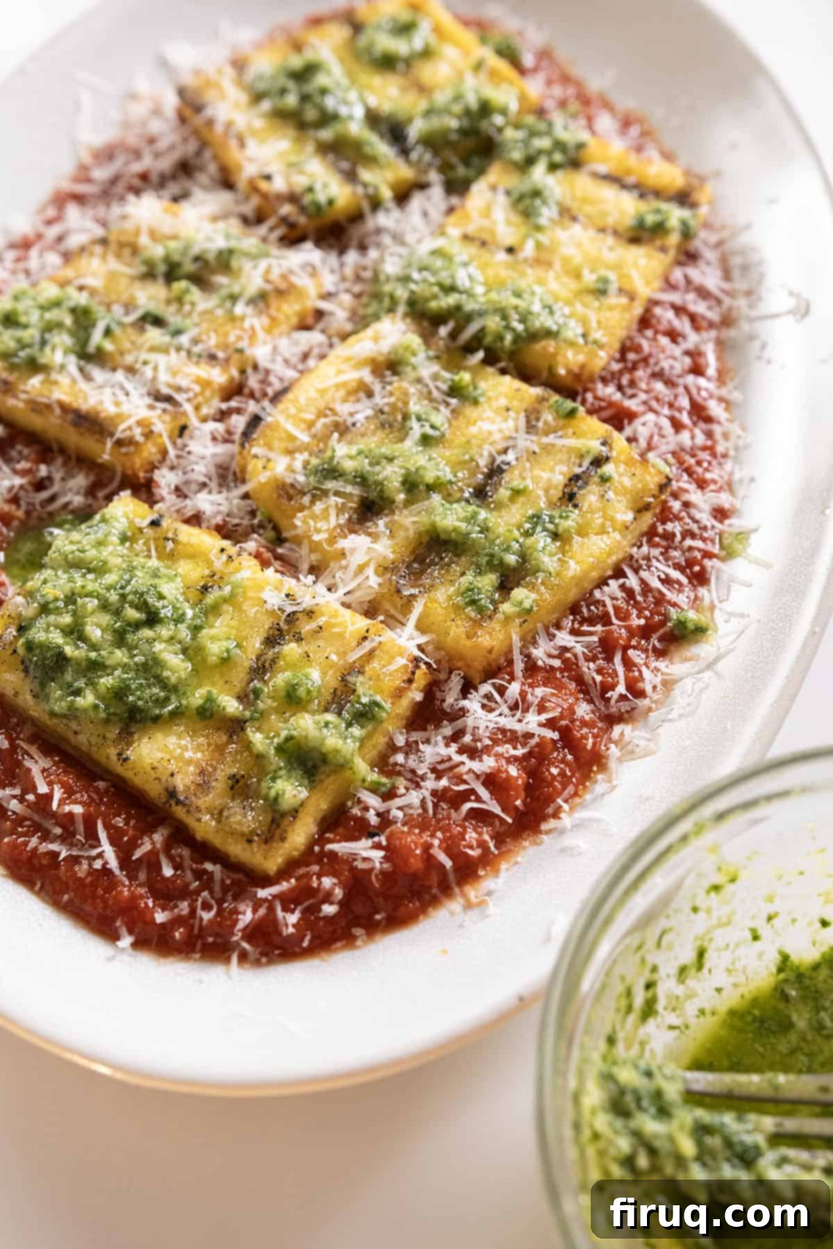 Golden Grilled Polenta with Marinara and Pesto 2 Perfectly grilled polenta squares served over a bed of rich marinara sauce, generously topped with fresh green pesto and grated Parmigiano cheese.