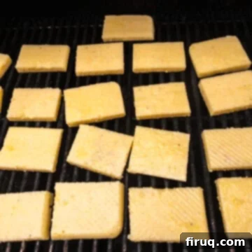 Golden Grilled Polenta with Marinara and Pesto 7 Polenta pieces grilling on hot grates, developing a golden crust.