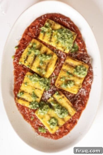 Golden Grilled Polenta with Marinara and Pesto 10 Grilled polenta squares plated on marinara, topped with fresh pesto and grated Parmigiano.