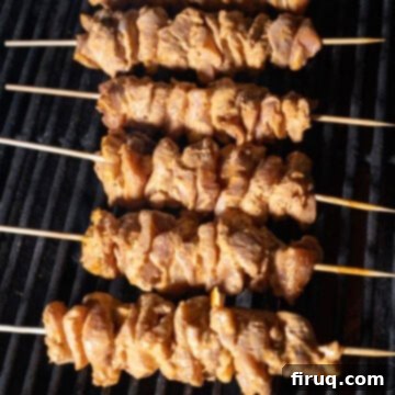 Zesty Bang Bang Chicken Skewers 9 Raw chicken skewers placed on the preheated grill, ready for basting.