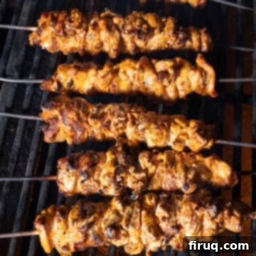 Zesty Bang Bang Chicken Skewers 10 Crispy, caramelized chicken skewers cooking on the grill, brushed with sauce.