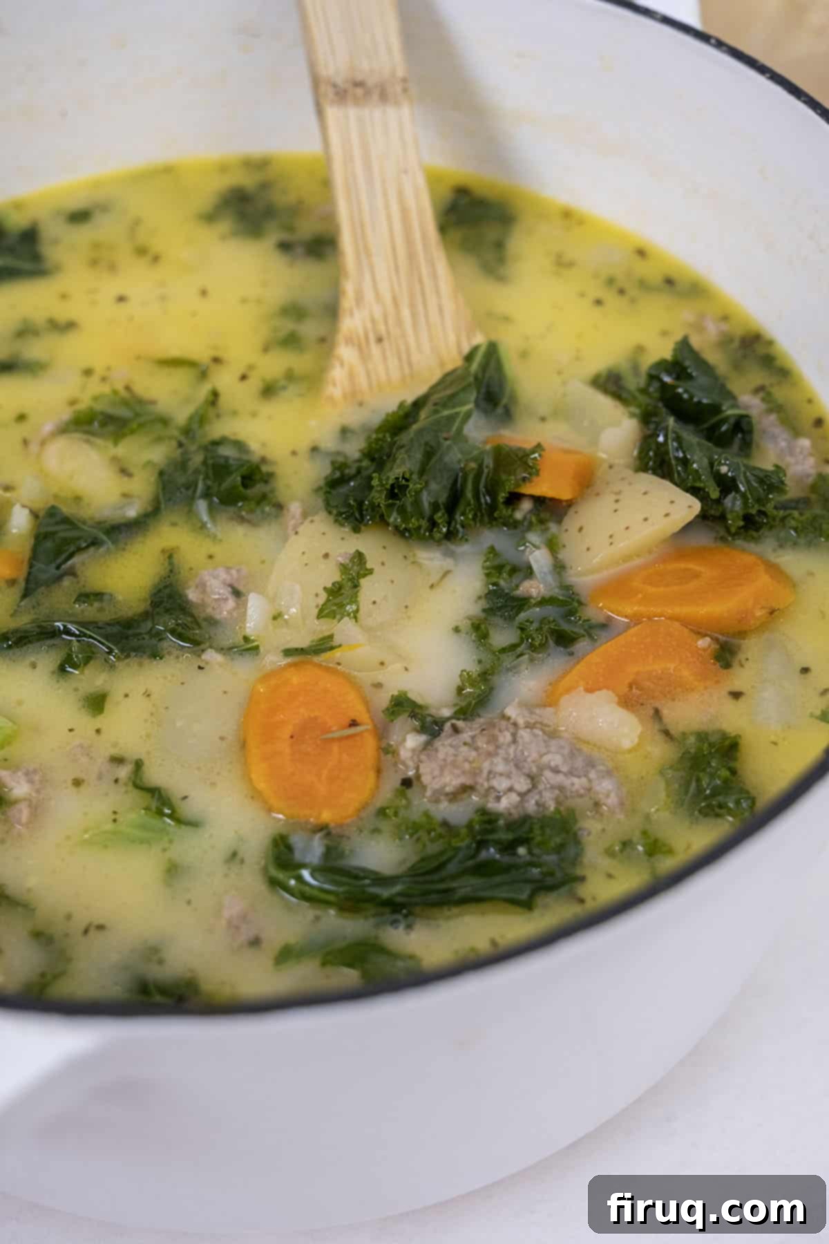 Creamy Tuscan Sausage and Potato Soup 2 A hearty bowl of Zuppa Toscana with carrots, potatoes, and Italian sausage, garnished with fresh herbs.