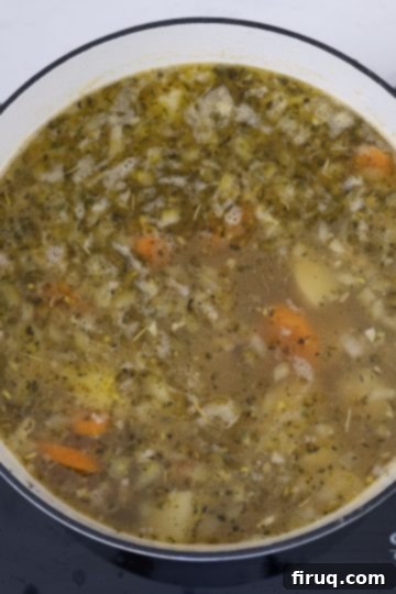 Creamy Tuscan Sausage and Potato Soup 7 Seasoning and diced potatoes being stirred into the soup base.