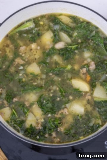 Creamy Tuscan Sausage and Potato Soup 9 Fresh kale being stirred into the simmering Zuppa Toscana until wilted.