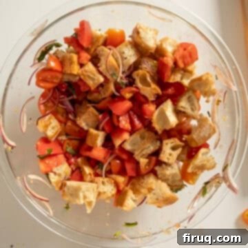 Rustic Tuscan Panzanella 8 Cubed bread soaking in a bowl with chopped tomatoes and vegetables, absorbing the dressing.