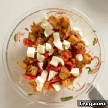 Rustic Tuscan Panzanella 9 Fresh mozzarella pieces being tossed into the Panzanella bread salad, adding a creamy texture.