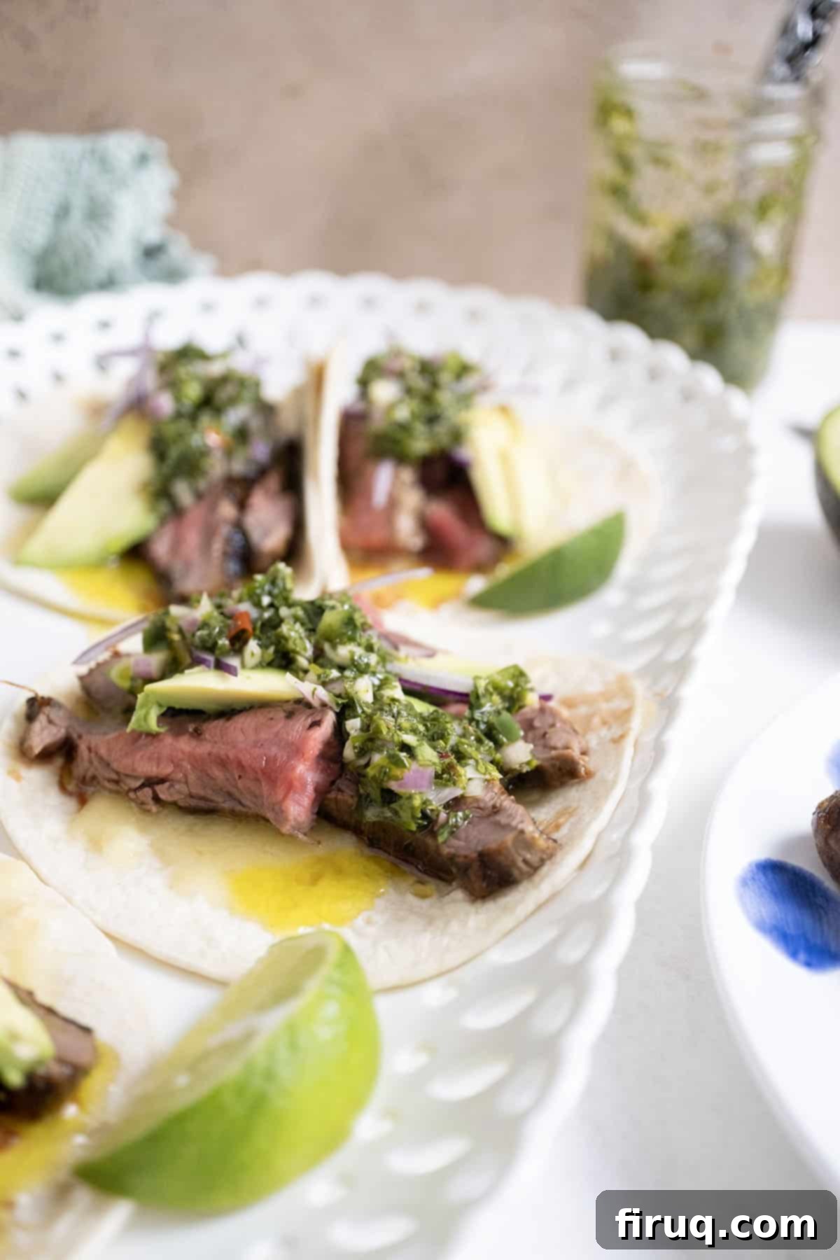 Vibrant Chimichurri Steak Tacos 13 Chimichurri steak tacos on a plate with limes.