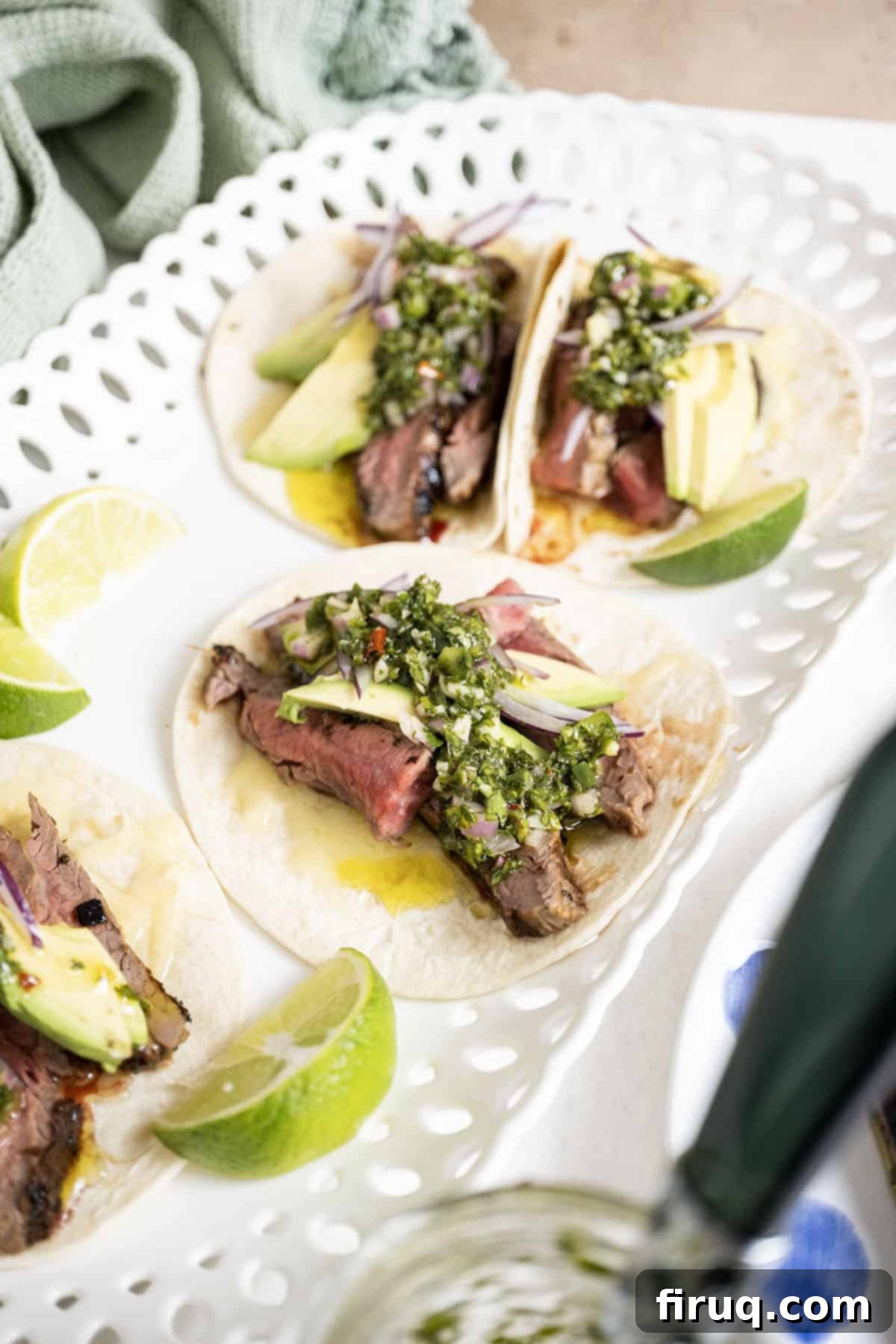 Vibrant Chimichurri Steak Tacos 14 Chimichurri steak tacos on a plate with limes.