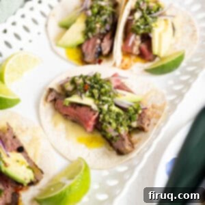 Vibrant Chimichurri Steak Tacos 15 Chimichurri steak tacos on a plate with limes.