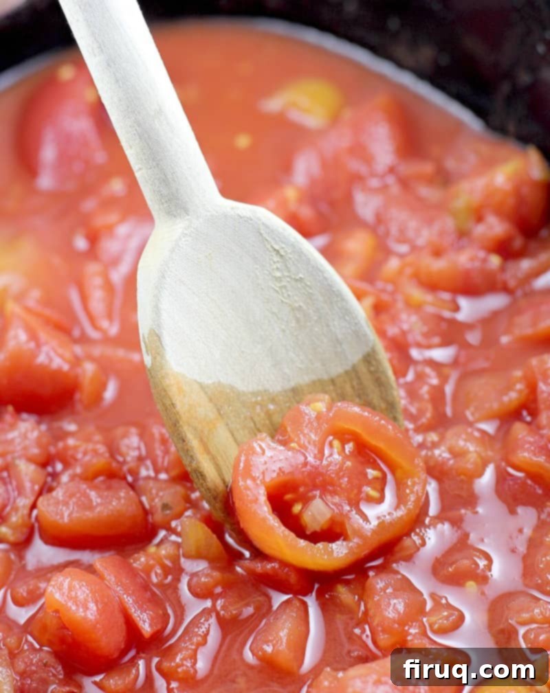 Yuletide Comfort Bowl 5 wooden spoon breaking up the stewed tomatoes