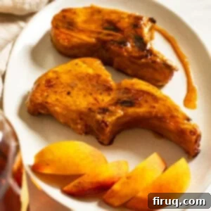 Pork Chops with Bourbon Peach Glaze 11 Bourbon peach glazed pork chops on a plate garnished with peaches and extra sauce.
