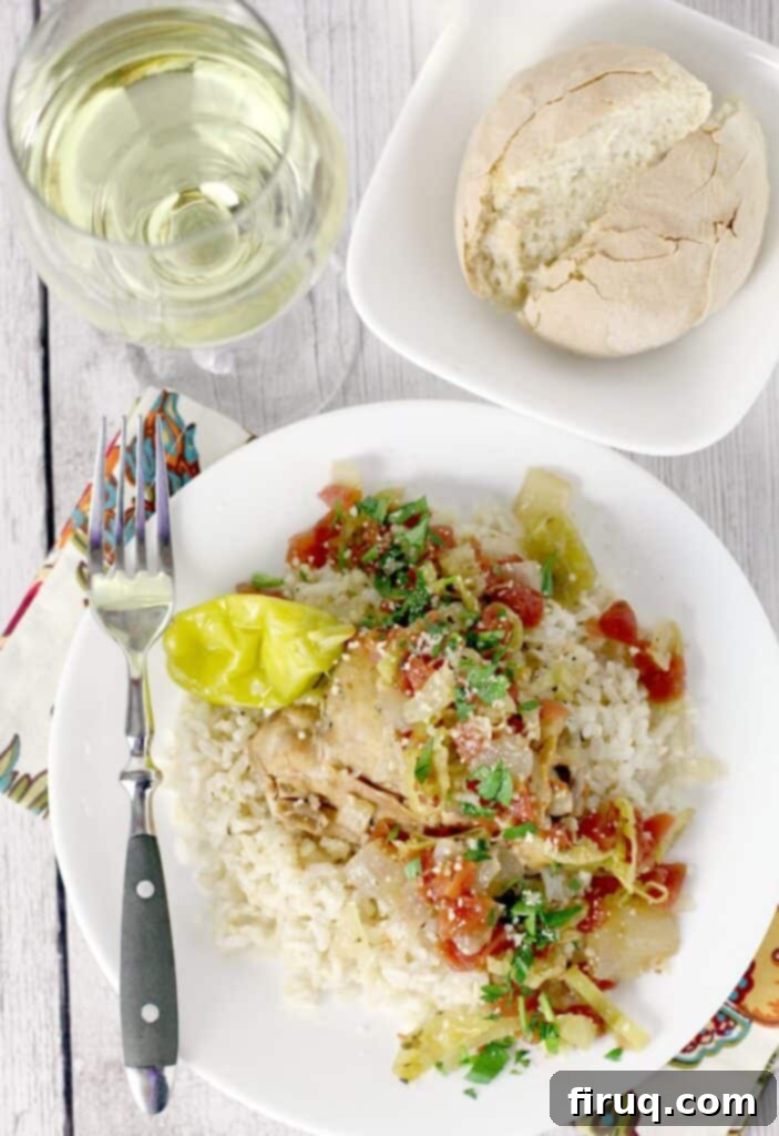 One-Pot Zesty Italian Pepperoncini Chicken 6 Top-down view showing cooked Slow Cooker Italian Pepperoncini Chicken served generously over rice on a white dish, with a fork on the side, and bread and a glass of white wine in the background, creating an inviting meal scene.