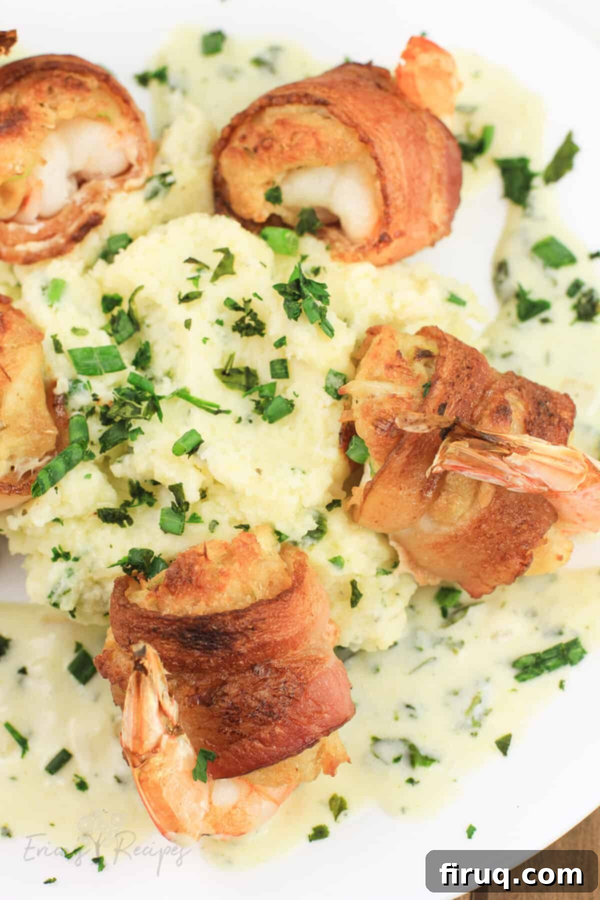 Crab Filled Shrimp with Bacon 9 bacon wrapped shrimp on white plate with mashed potatoes and lemon basil cream sauce