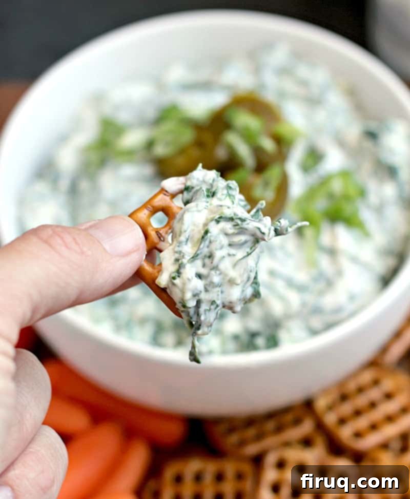 Zesty Slim Spinach Dip 3 hand holding a pretzel with dip on it