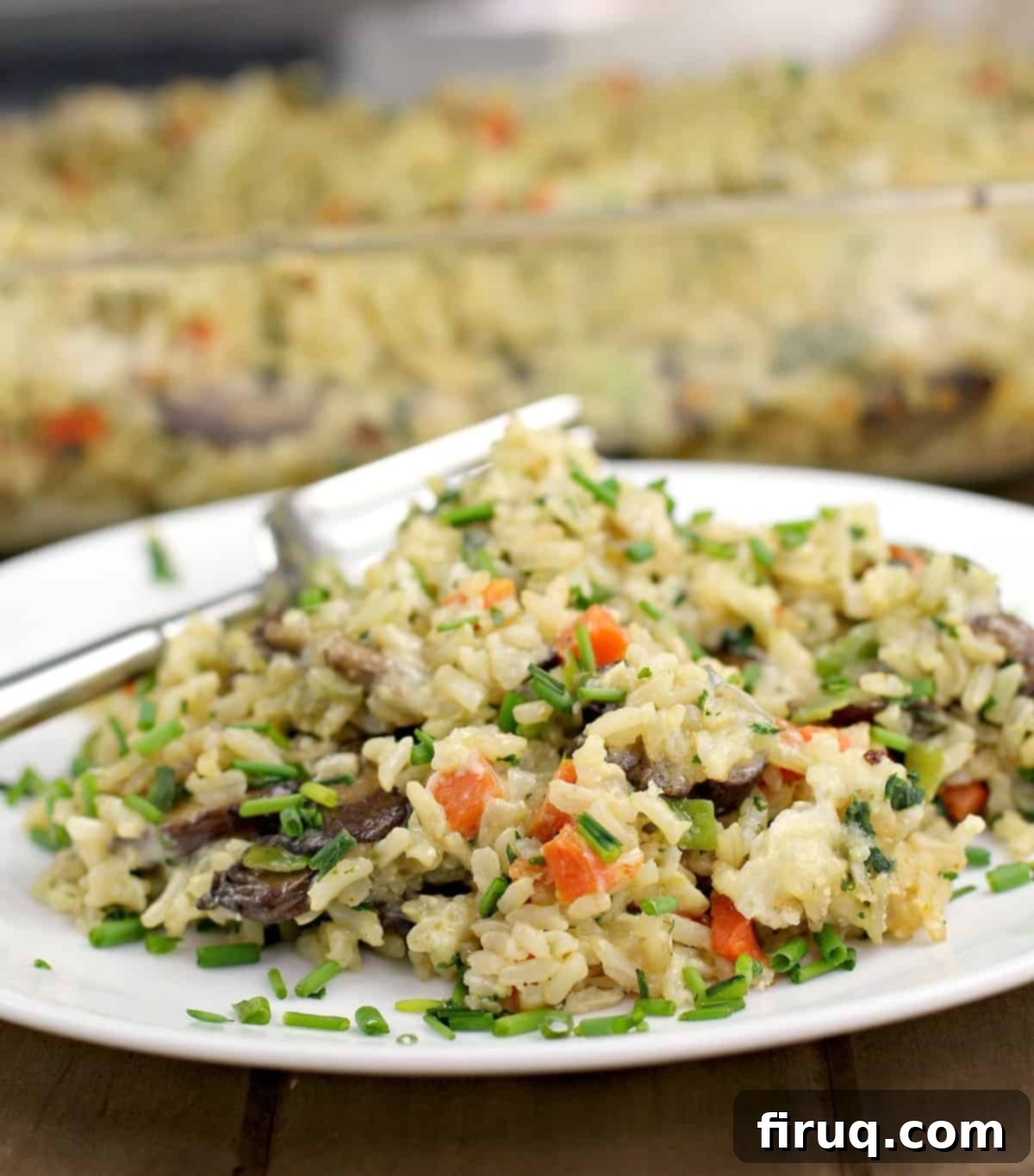 Comforting Veggie Rice Bake 15 brown rice casserole on a white plate with fork; bake dish in the back ground