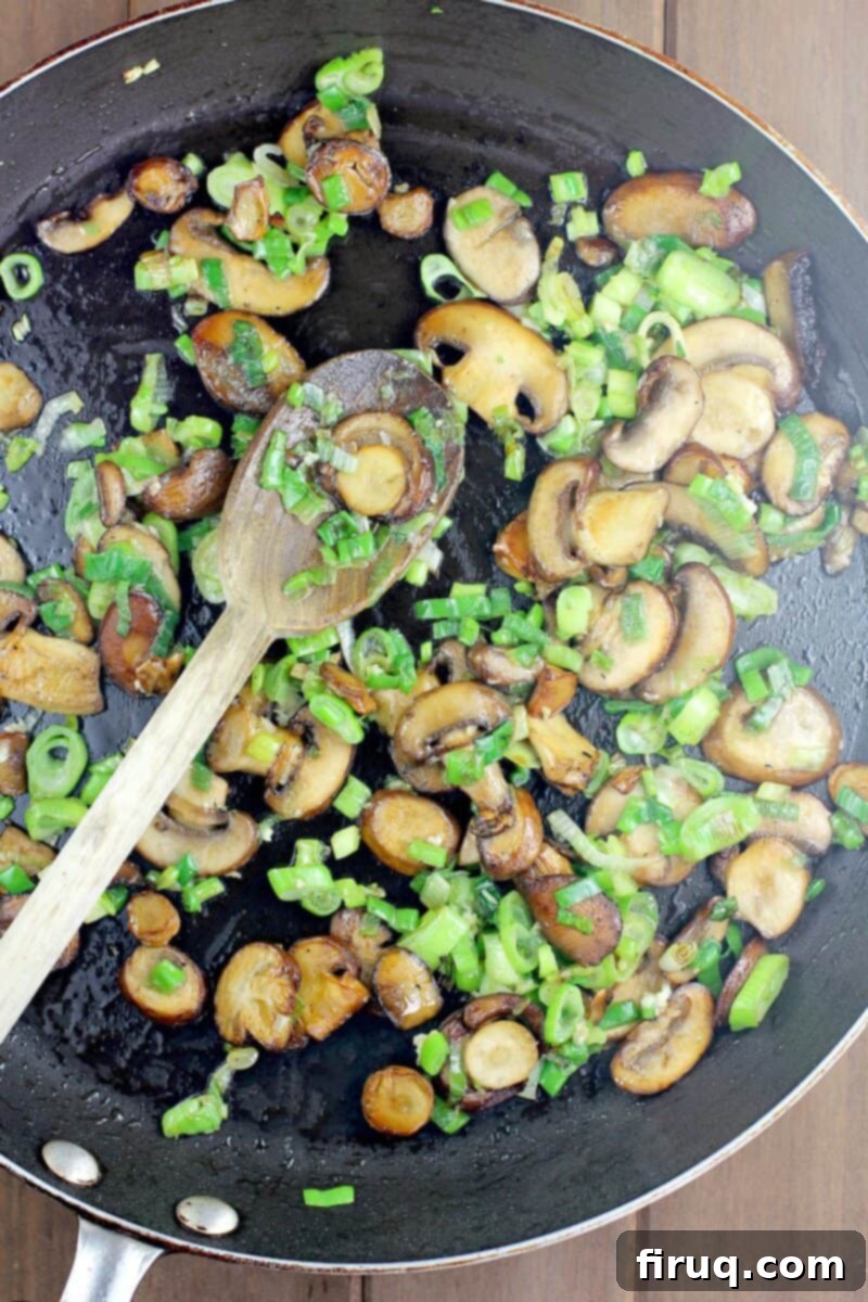Comforting Veggie Rice Bake 10 browned mushrooms and green onion with wooden spoon in black skillet