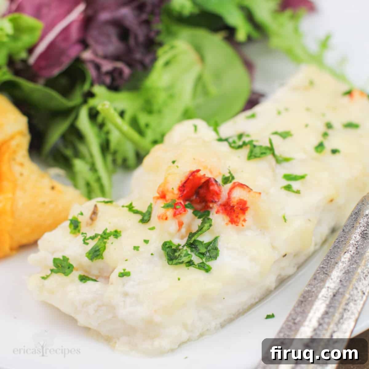Oven-Baked Haddock, Lobster-Kissed 2 portion of prepared haddock with lobster sauce on white plate with salad and roll