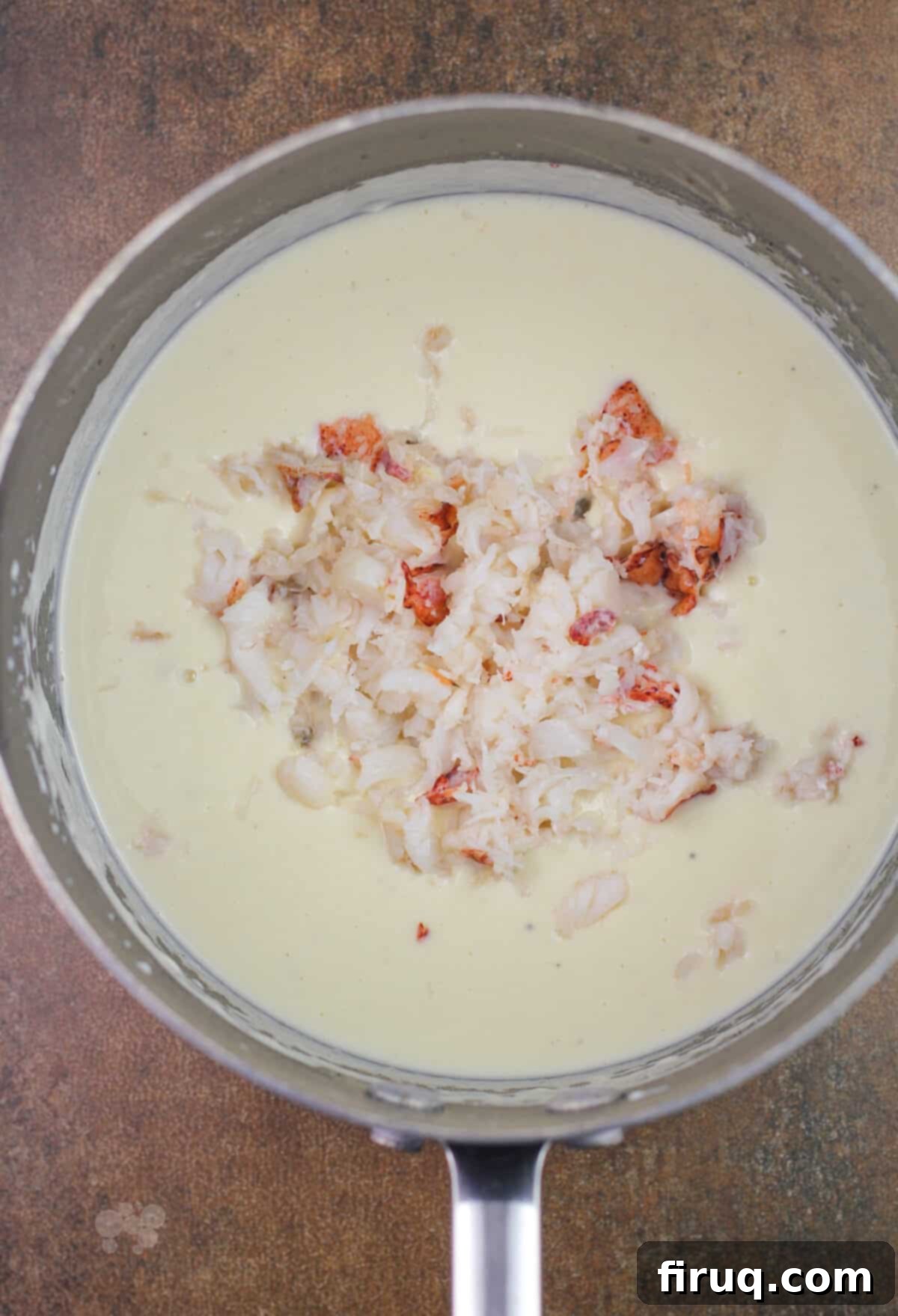 Oven-Baked Haddock, Lobster-Kissed 5 lobster in the center of white bechamel in saucepan